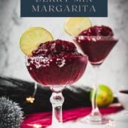 Magnificent frozen mixed berry margarita, served in cocktail glasses, garnished with a lime slice. With a vibrant dark red color. What an eye-catcher!