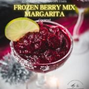 Magnificent frozen mixed berry margarita, served in cocktail glasses, garnished with a lime slice. With a vibrant dark red color. What an eye-catcher!