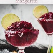 Magnificent frozen mixed berry margarita, served in cocktail glasses, garnished with a lime slice. With a vibrant dark red color. What an eye-catcher!