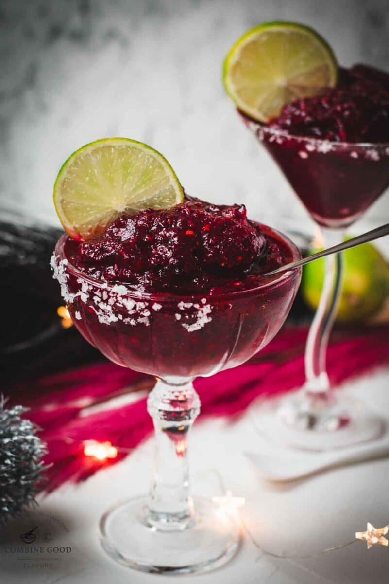 Magnificent frozen mixed berry margarita, served in cocktail glasses, garnished with a lime slice. With a vibrant dark red color. What an eye-catcher!