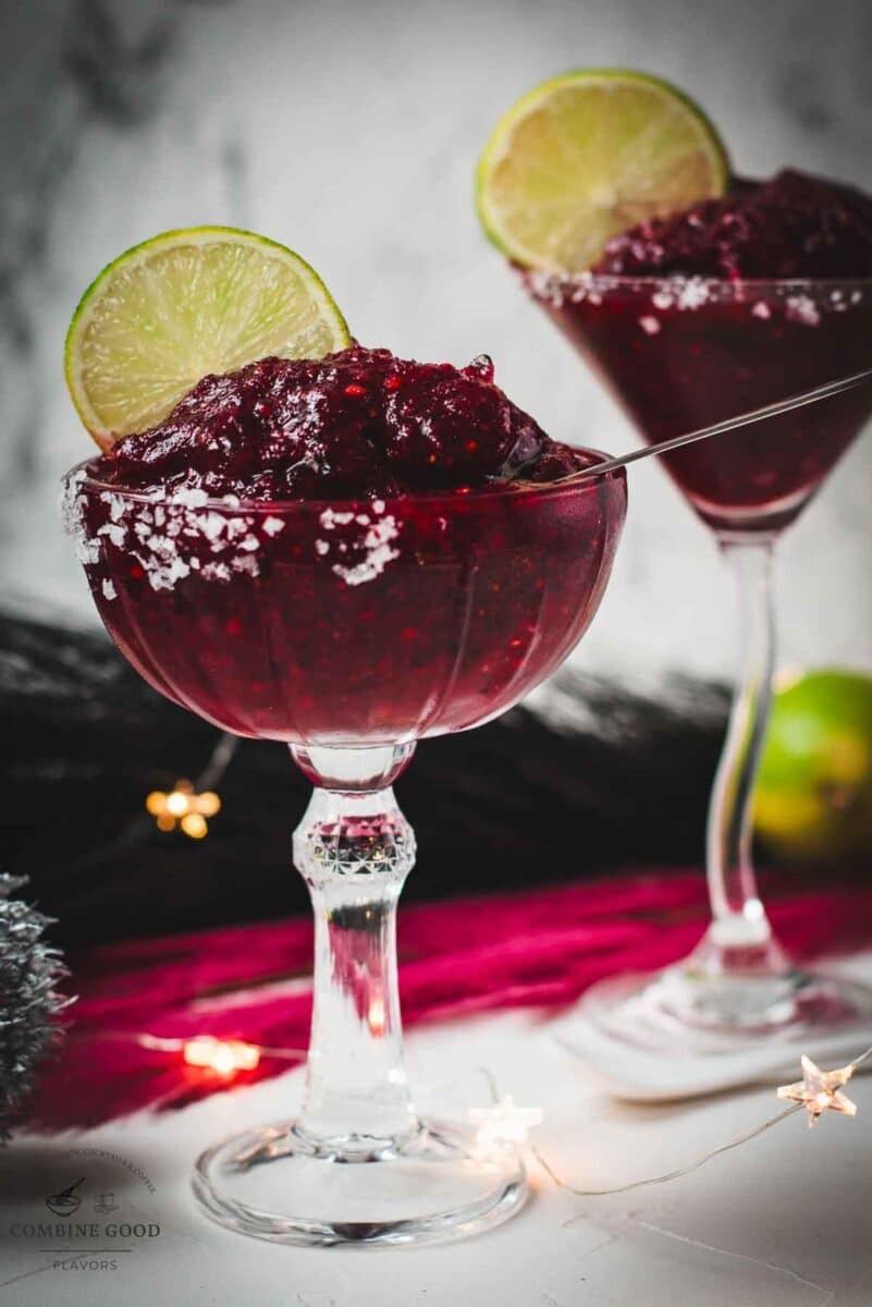 Magnificent frozen mixed berry margarita, served in cocktail glasses, garnished with a lime slice. With a vibrant dark red color. What an eye-catcher!