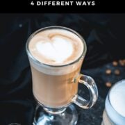 2 glasses filled with delicious vanilla latte. placed on dark ground. Left on has a latte art heart on top.
