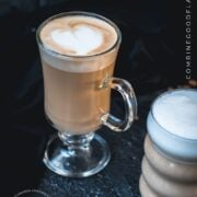 2 glasses filled with delicious vanilla latte. placed on dark ground. Left on has a latte art heart on top.