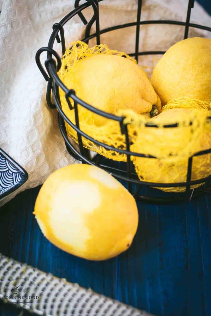 Zested lemon next to a lemon zester and a bowl full of lemons.