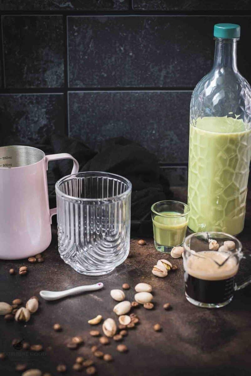 Ingredients for a boozy pistachio latte - double espresso, creamy pistachio liqueur, milk, whipped cream and crushed pistachios.