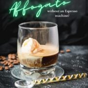 A scoop of vanilla ice cream sits in a glass of dark espresso on a black surface, making a perfect affogato.