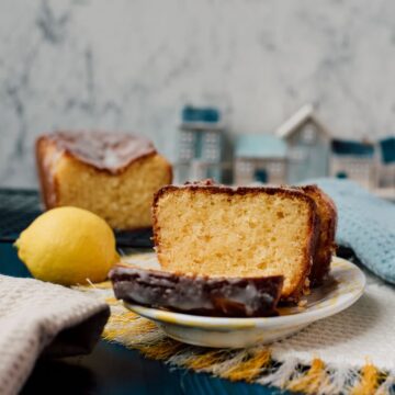 Sliced lemon loaf cake, placed on white and yellow plate, next a lemon.