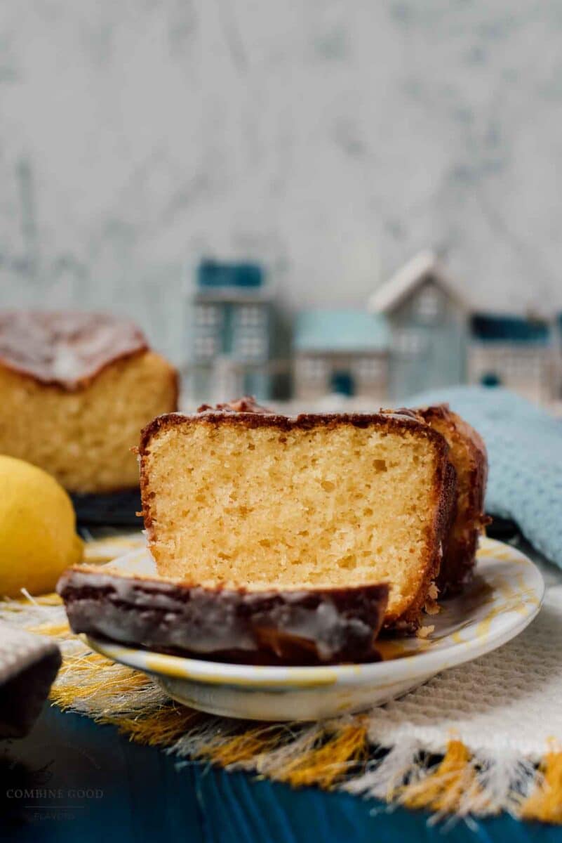 Sliced lemon loaf cake, placed on white and yellow plate, next a lemon.