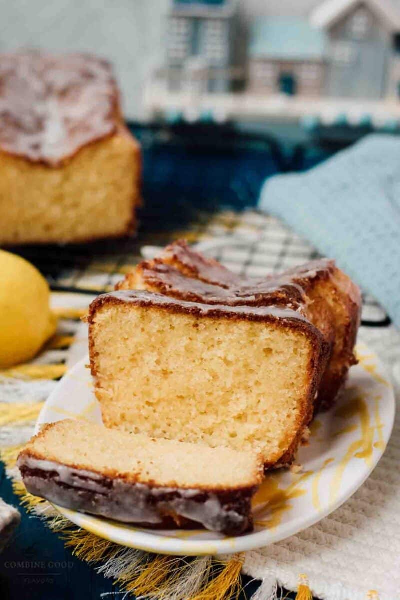 Sliced lemon loaf cake, placed on white and yellow plate, next a lemon.