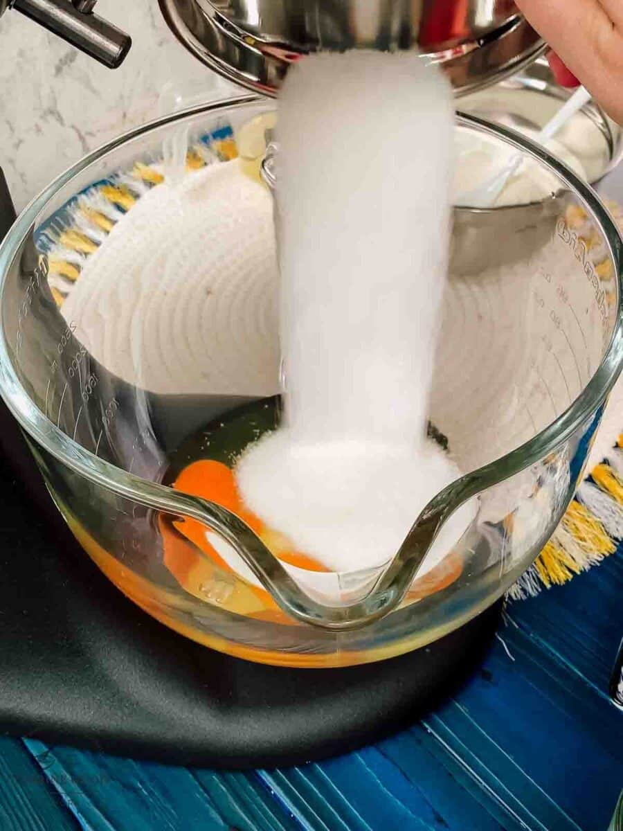 Pouring granulated sugar into the mixing bowl.