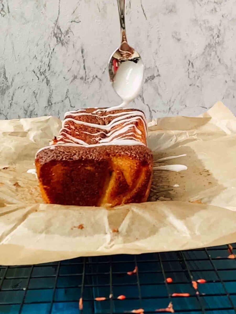 Drizzling homemade lemon glaze over the freshly baked lemon loaf cake.