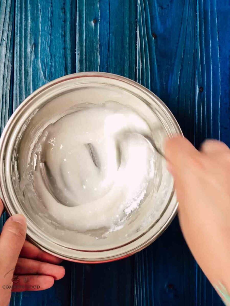 Mixing the powdered sugar with the lemon juice, using a fork.