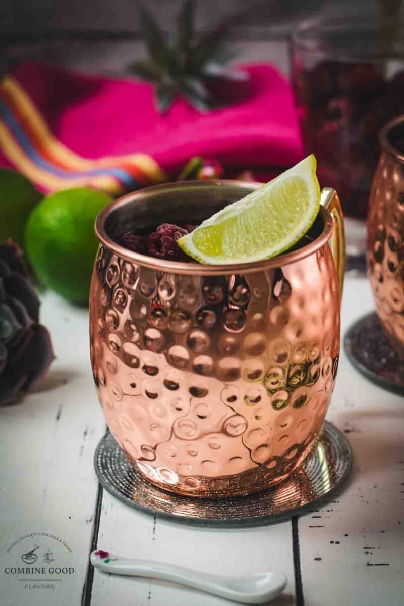 close-up of a delicious raspberry mule served in hammered copper mugs on mirrored coasters.