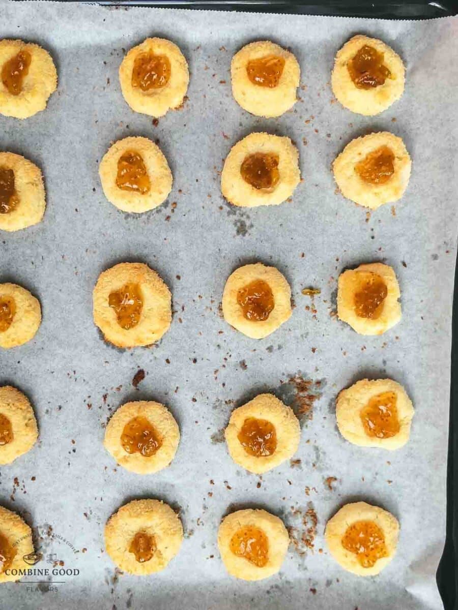 Fig jam cookies on a baking sheet, already filled with fig jam after baking.