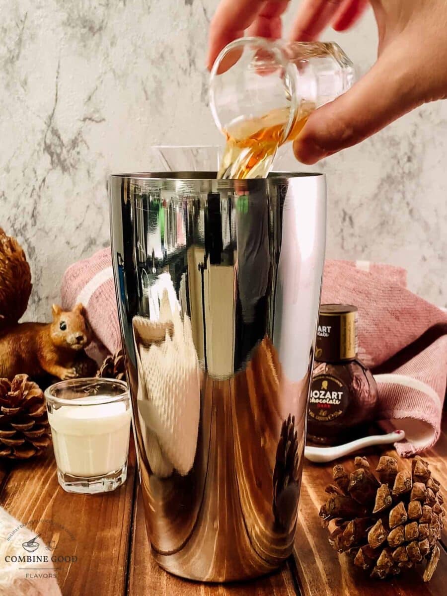 Pouring Cognac into an ice-filled cocktail shaker