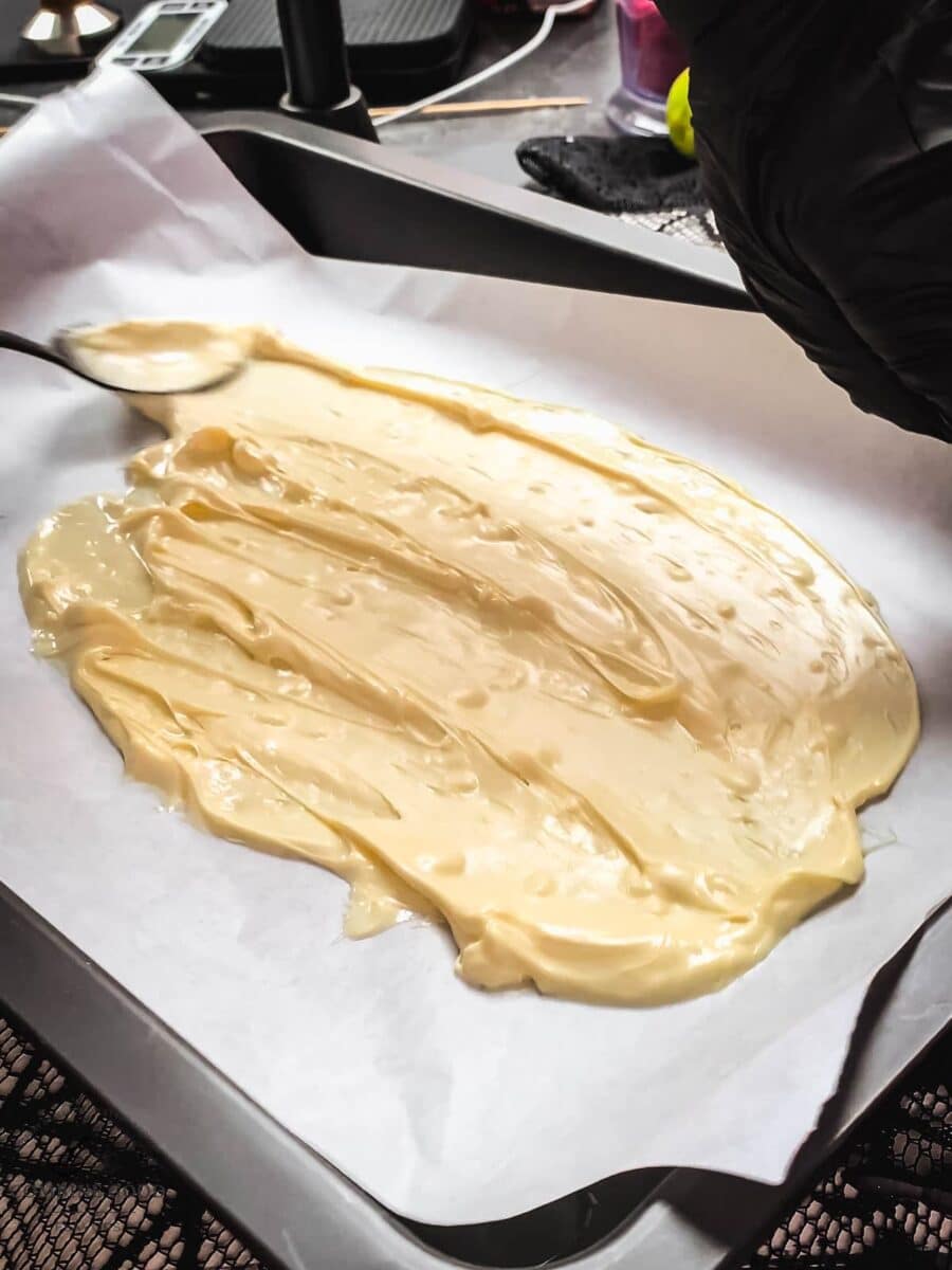 Spread the melted white chocolate into the parchment paper lined tray.