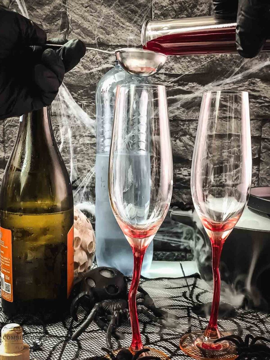 Measure the berry blood syrup before pouring it into the cocktail glass.