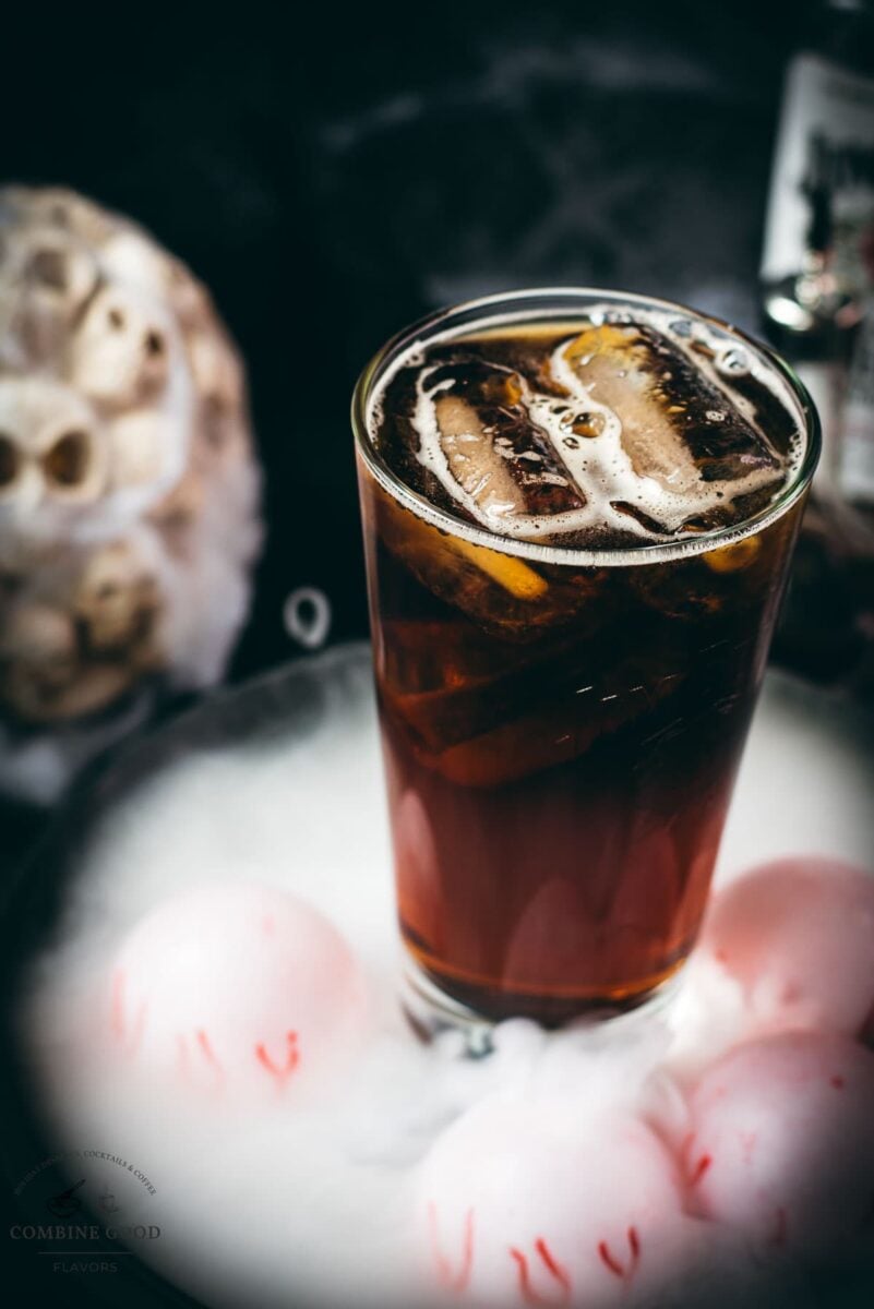 Close-up of a dark bourbon and root beer cocktail served over ice.
