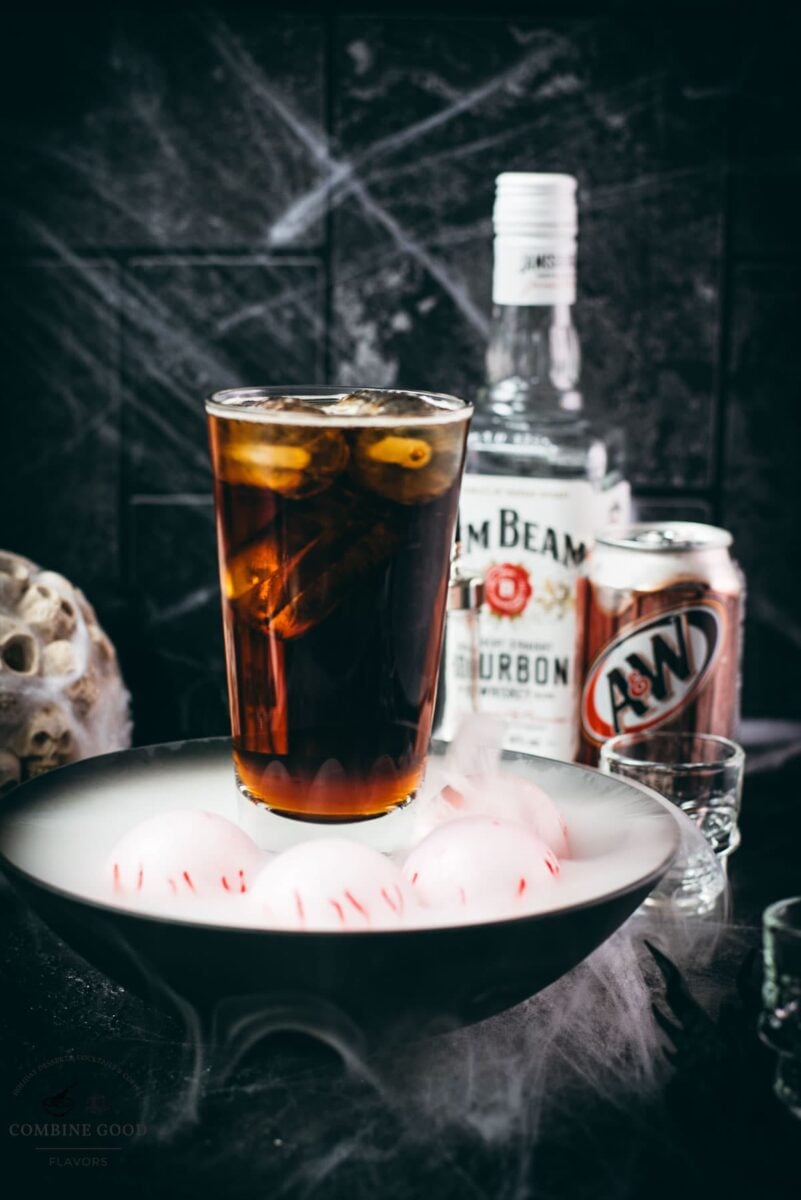 Bourbon root beer cocktail with a skull shot glass and black dragon coaster.