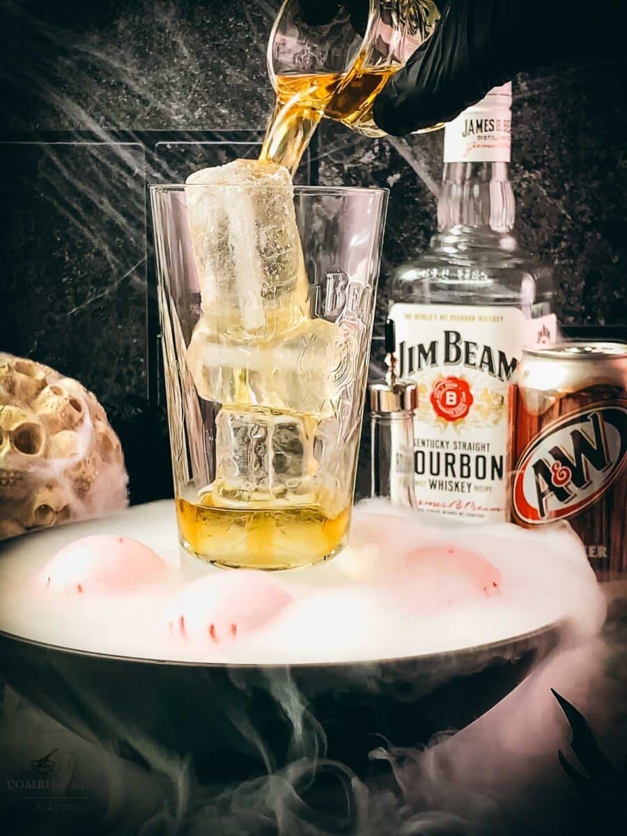 Bourbon being poured over ice into a tall cocktail glass.