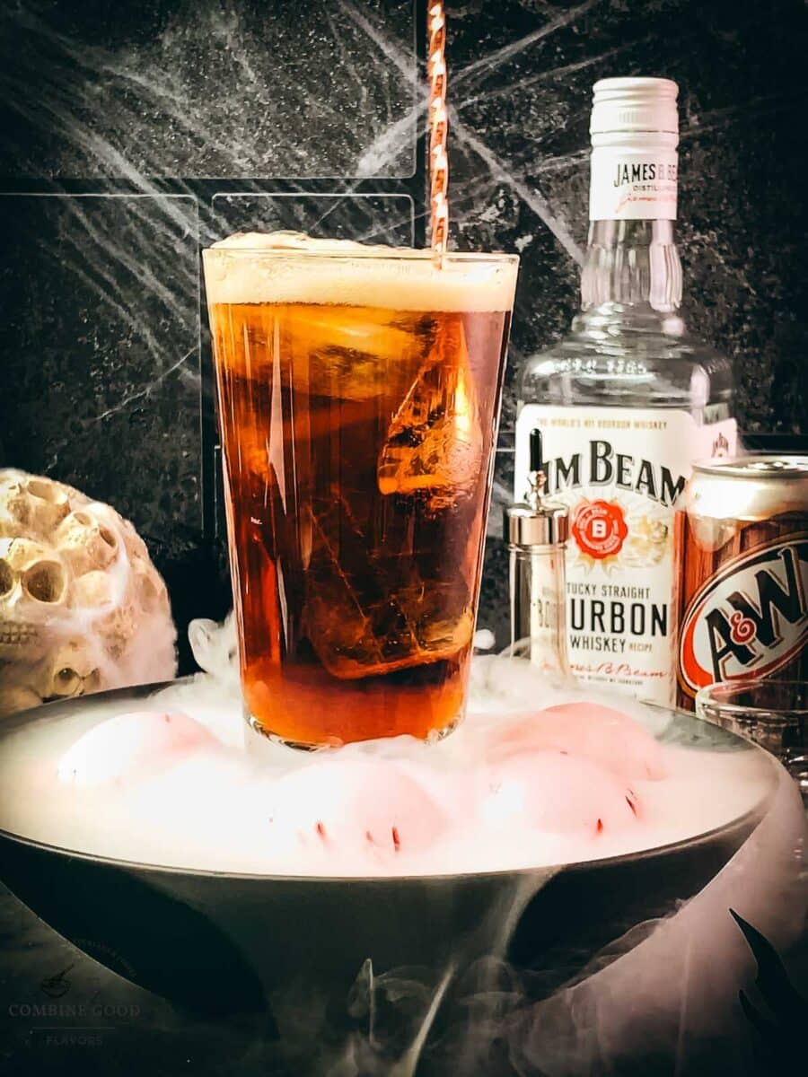 Bourbon and root beer cocktail being gently stirred with a bar spoon.