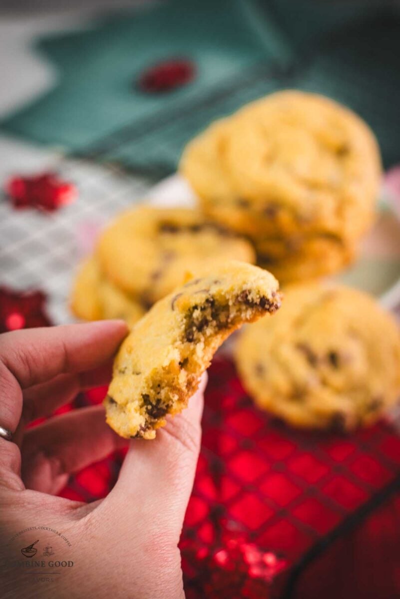 Hand holding a broken chocolate chip cookie showing its thick, soft center.