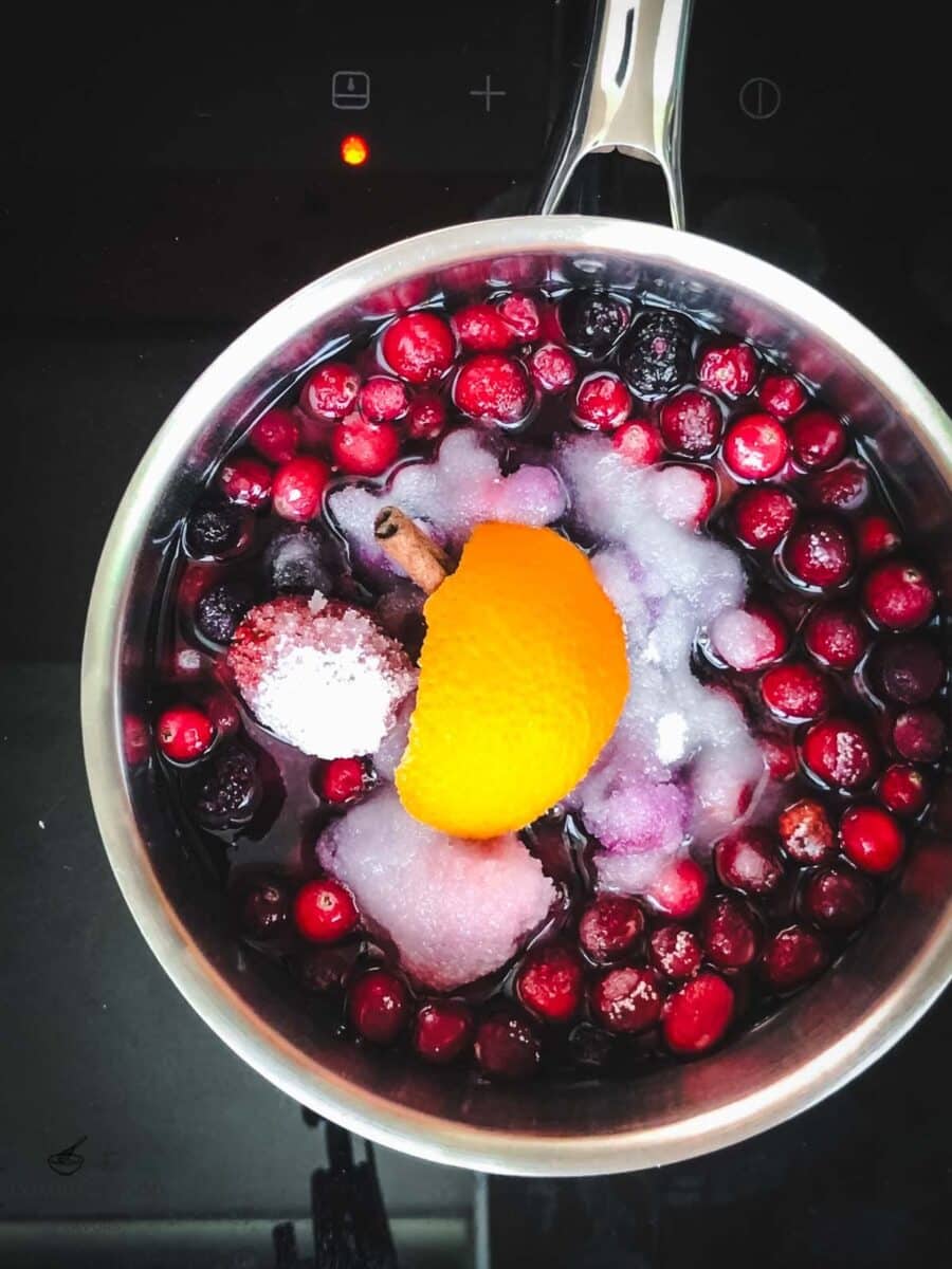 Cranberries, mixed berries, sugar, water, orange peel, and cinnamon in a saucepan before cooking