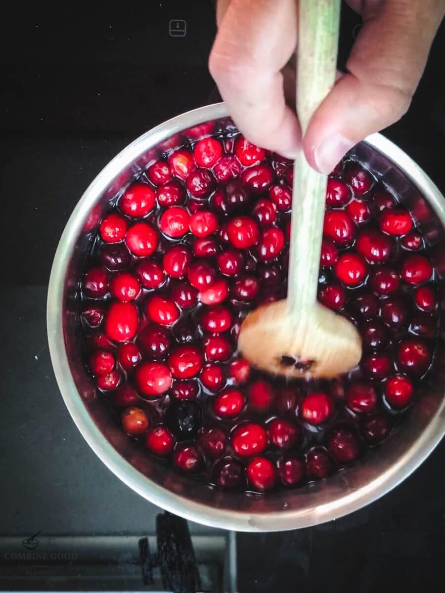 Stirring the simmered cranberry and mixed berry syrup with a wooden spoon