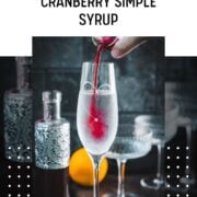 Cranberry simple syrup being poured into a tall glass of sparkling water