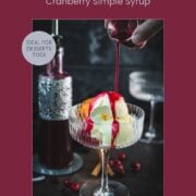 Cranberry simple syrup being poured over vanilla ice cream in a cocktail glass