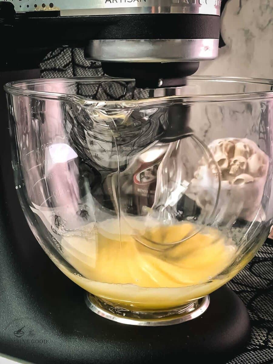 Side view of egg and sugar being mixed in a KitchenAid stand mixer.