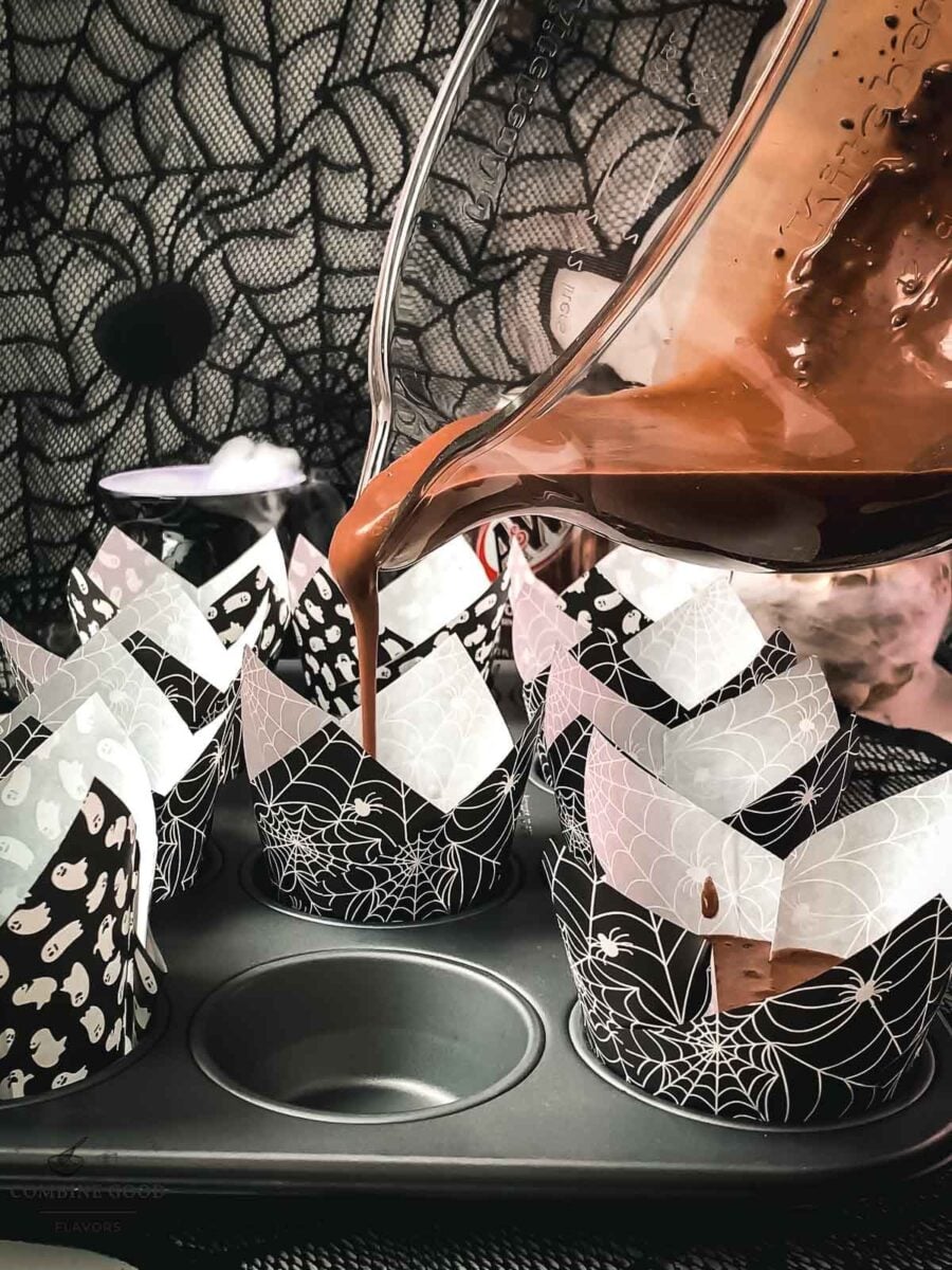 Pouring chocolate root beer muffin batter into a Halloween tulip liner