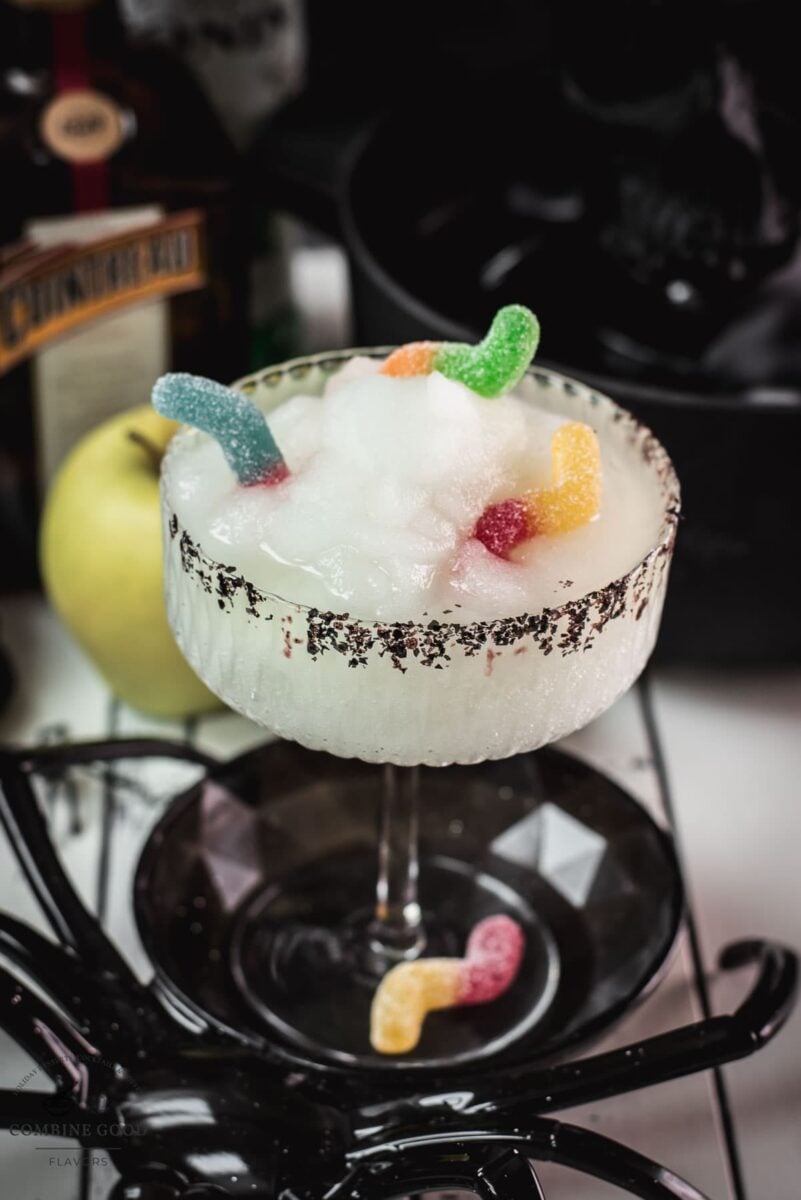 Bright green frozen Halloween Margarita with black sugar rim and gummy worms
