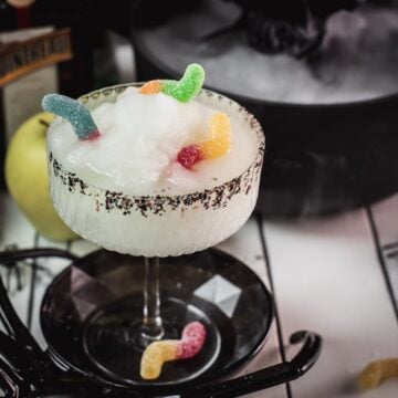 Finished green frozen margarita with black sugar and gummy worms