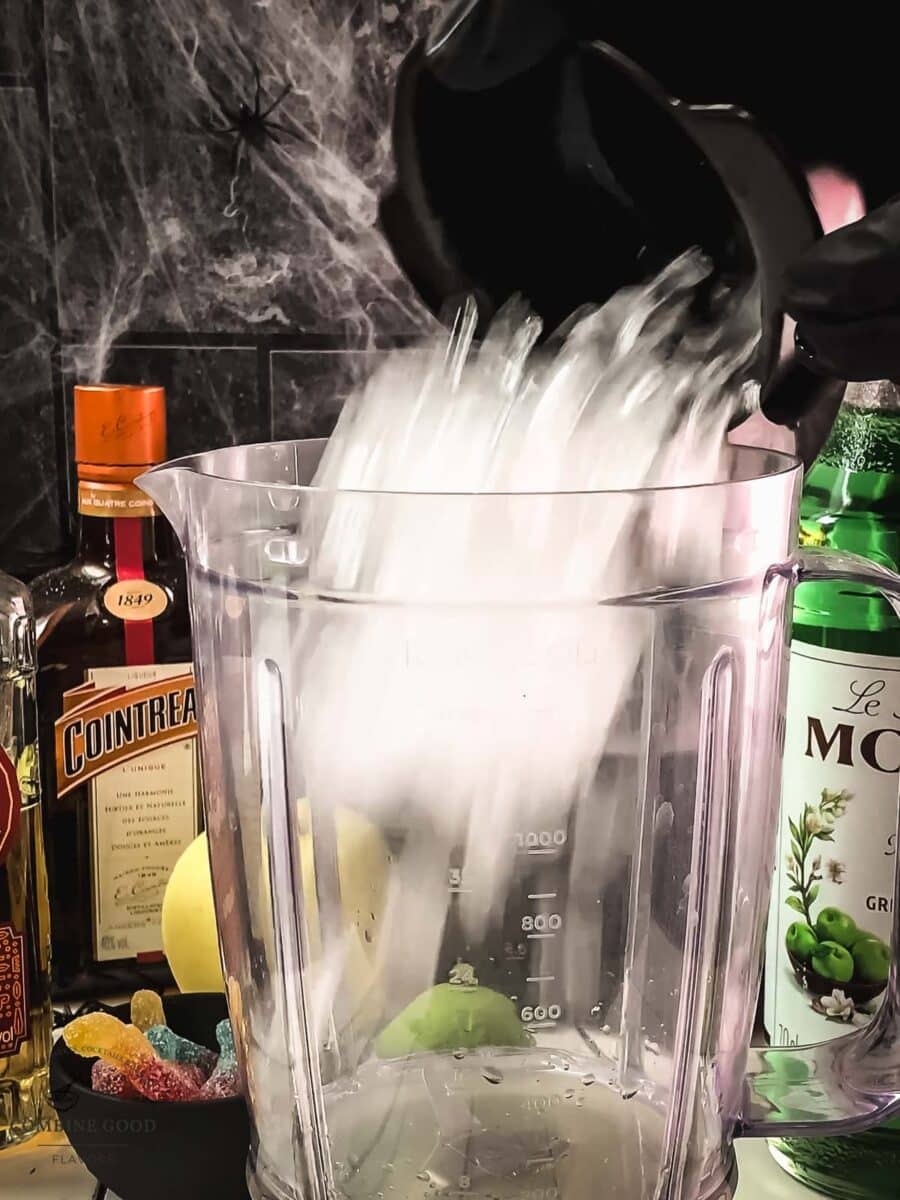 Ice added to green margarita ingredients in a blender