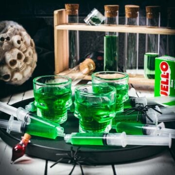Halloween Jello shot syringes on a black plate over white wooden planks