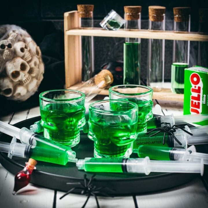 Halloween Jello shot syringes on a black plate over white wooden planks