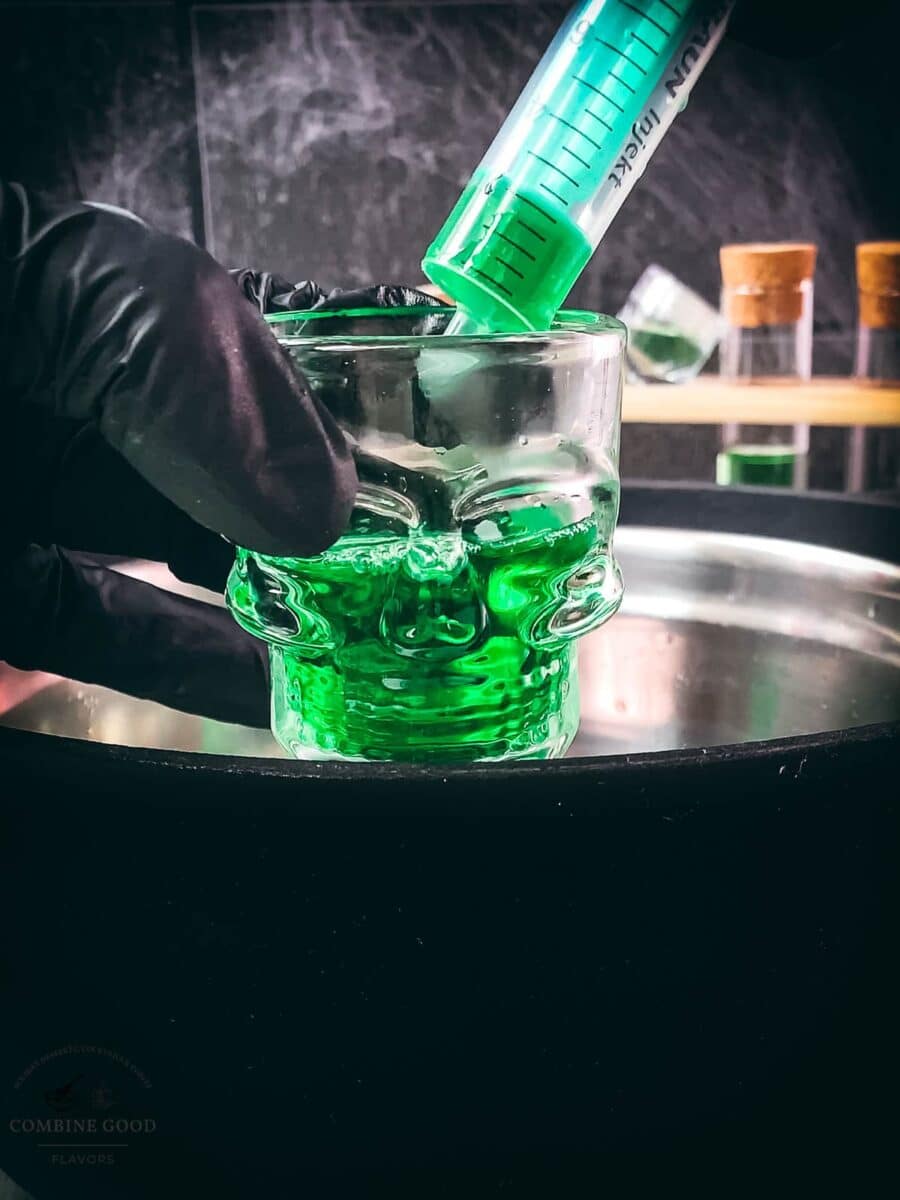 Green Halloween Jello mixture poured into skull shot glasses