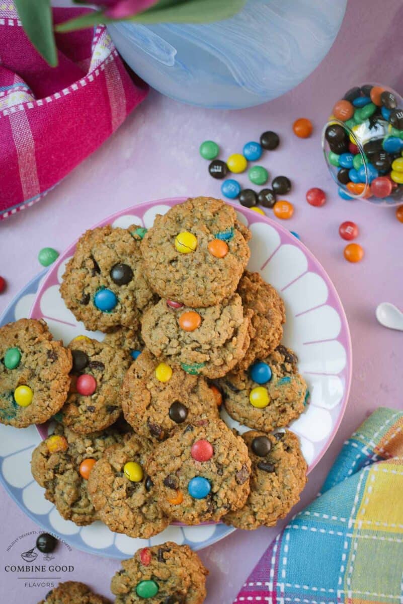Stack of chewy oatmeal M&M chocolate chip cookies showing textured oats and colorful candy pieces.