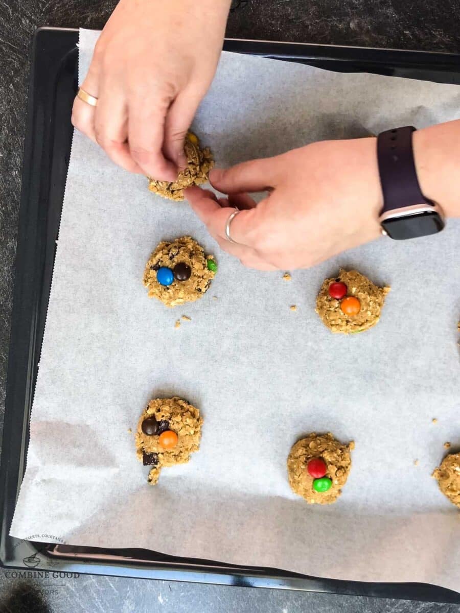 Extra M&M’s and chocolate chips pressed into scoops of oatmeal cookie dough before baking.