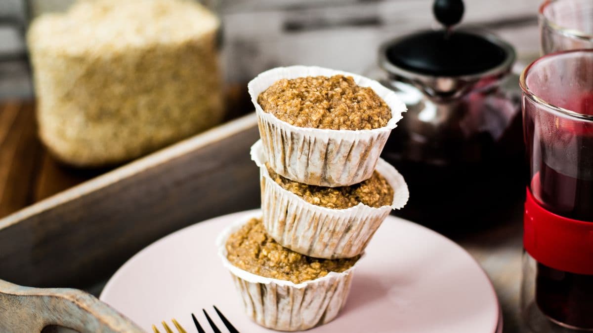 A magnificent tower of banana oatmeal muffins on a wooden tray. Behind it, delicious red tea.