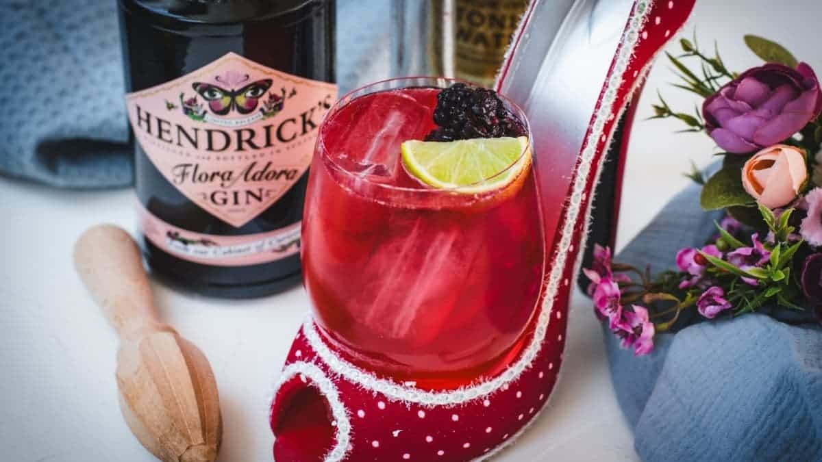 Chambord gin and tonic playfully placed in a red and white polka dot high heel. Garnished with a lime wedge and a black berry.