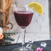 Elegant, dark red beetroot sour, garnished with a lemon wedge. Placed on a black slate plate.