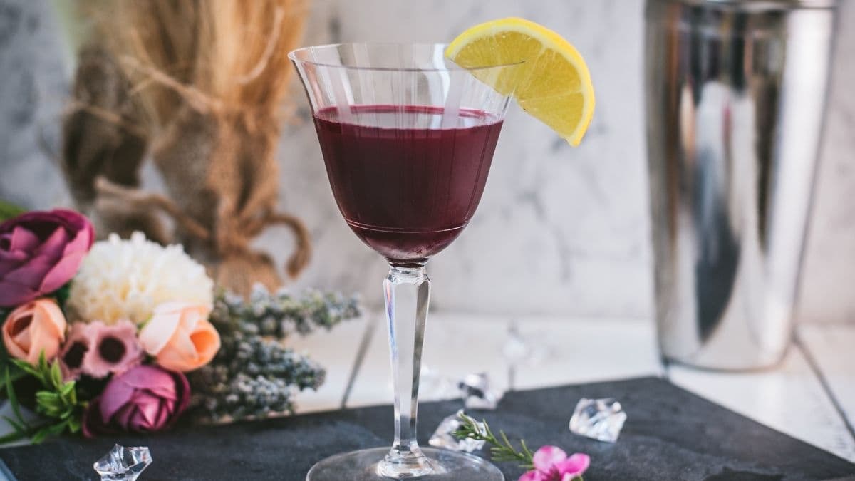 Elegant, dark red beetroot sour, garnished with a lemon wedge. Placed on a black slate plate.