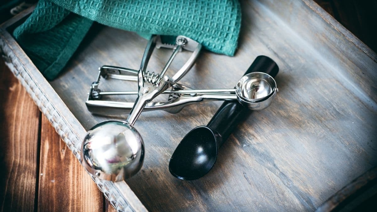 Three different cookie scoops displayed on a wooden tray.