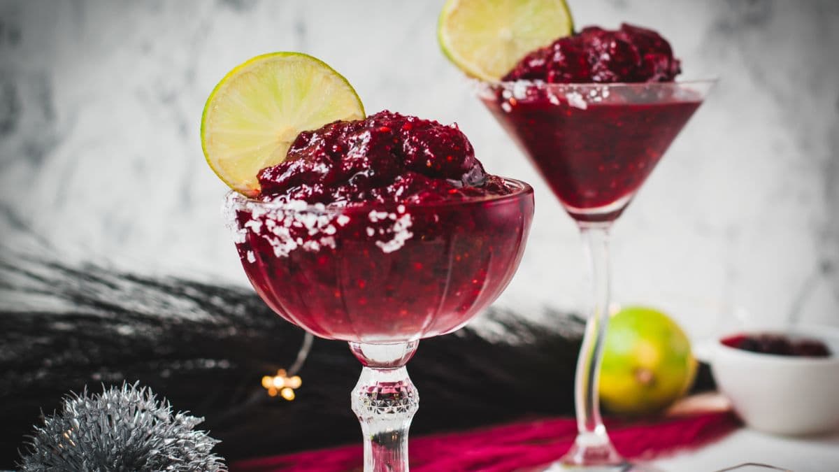 Magnificent frozen mixed berry margarita, served in cocktail glasses, garnished with a lime slice. With a vibrant dark red color. What an eye-catcher!