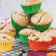 cute fruit and nut muffins with colored lines, stacked on cooling rack.