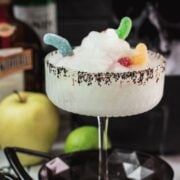 Poison apple margarita with black sugar and gummy worm garnish