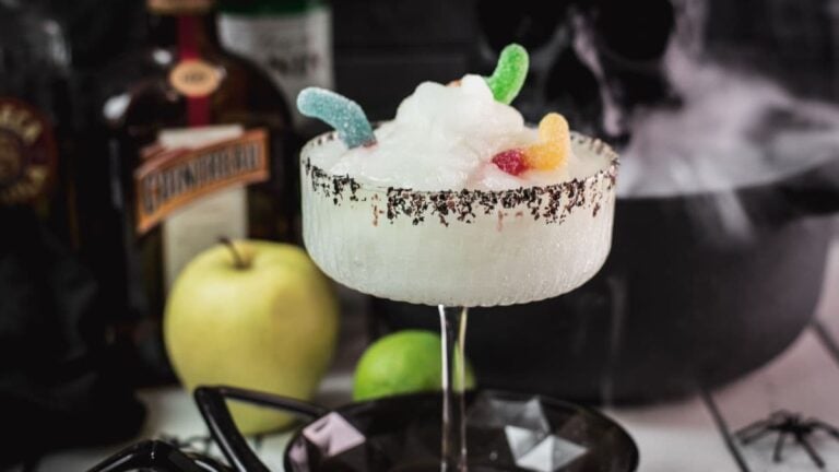 Poison apple margarita with black sugar and gummy worm garnish