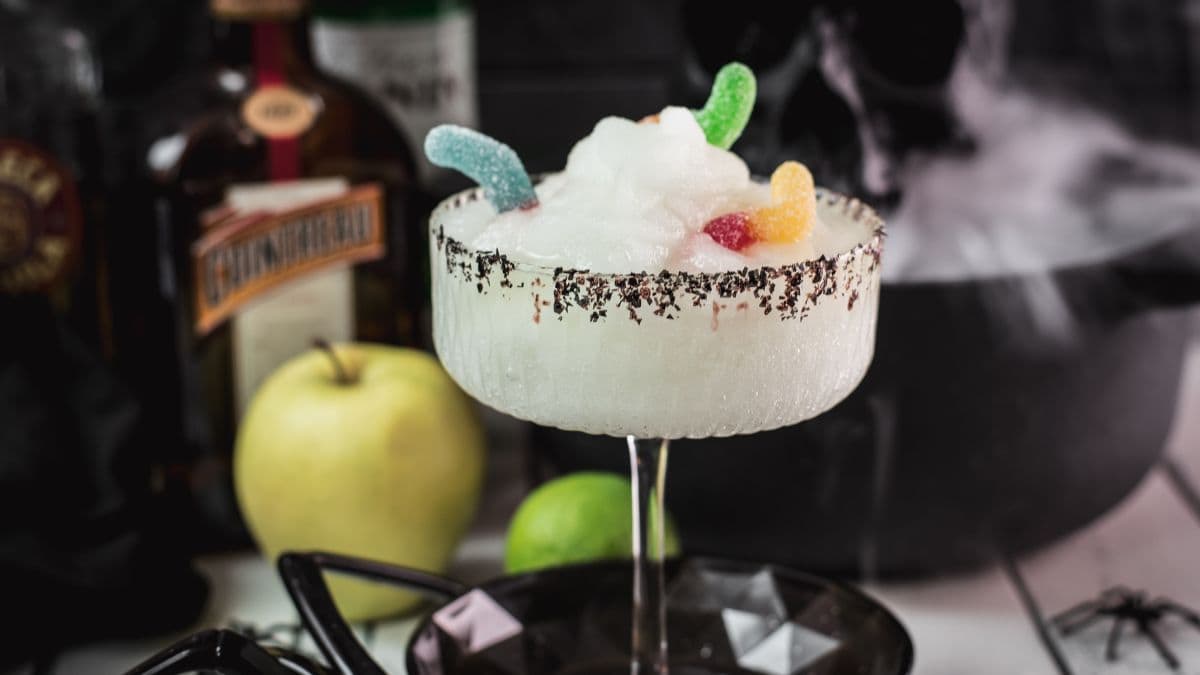 Poison apple margarita with black sugar and gummy worm garnish